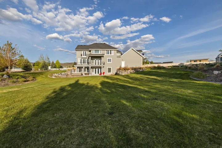 Expansive rear yard featuring a manicured lawn and multi-level landscaping
