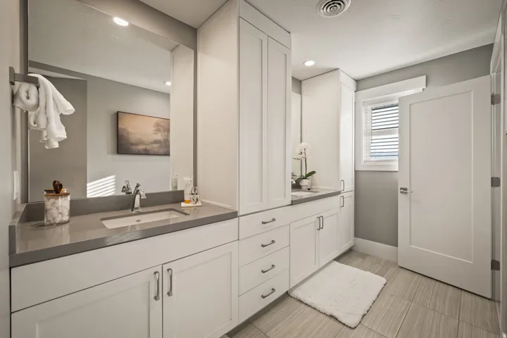 Bathroom featuring a dual vanity with white shaker cabinetry, gray countertops, and integrated sinks