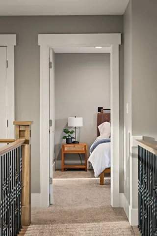 Carpeted hallway with painted walls and white trim, featuring a bedroom entry with integrated lighting