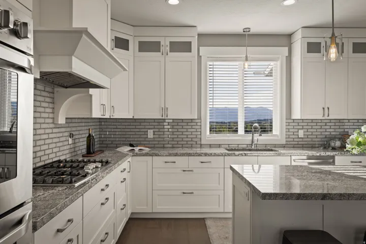 Kitchen featuring white shaker-style cabinetry, stainless steel appliances including a gas range and built-in oven, and a large central island