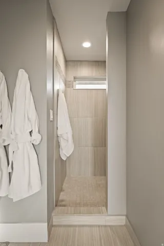 Tiled shower enclosure featuring a recessed window, a mosaic tile floor, large format wall tiles, and recessed lighting