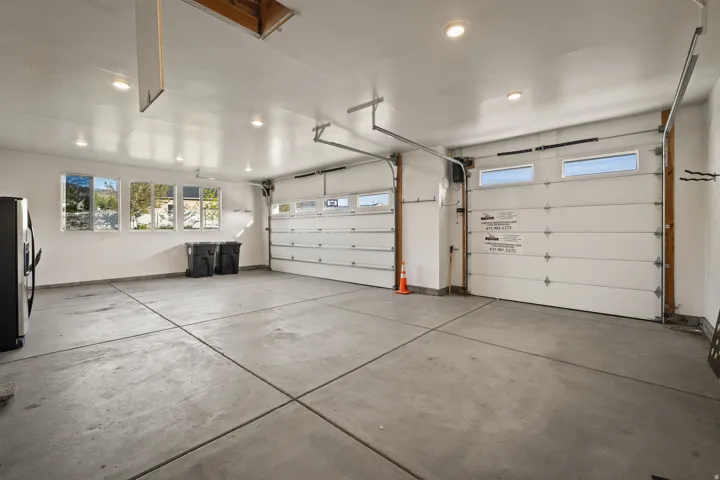 Spacious garage featuring two overhead doors, multiple windows, recessed lighting, and a concrete floor
