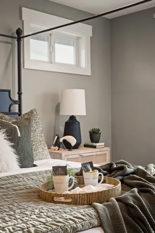 Bedroom featuring a transom window with white trim, light gray painted walls, and a light wood-finish nightstand