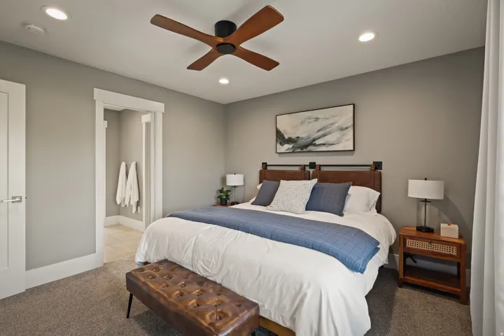 Carpeted bedroom featuring a ceiling fan with wood-finish blades, recessed lighting, a door with modern hardware, and an entryway with white trim
