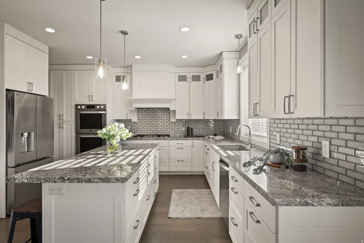 Bright kitchen featuring white cabinetry and light-toned granite countertops