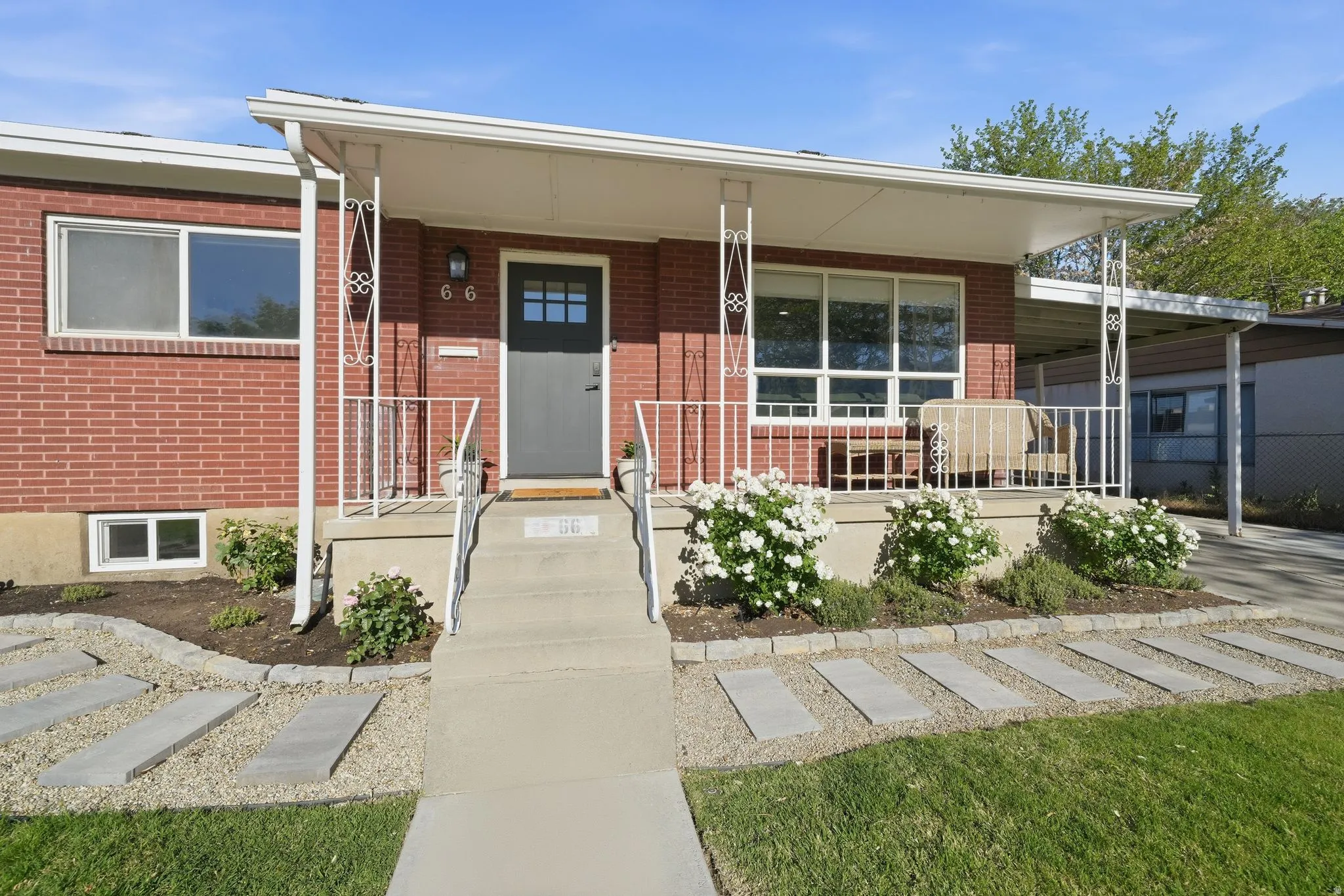 Brick exterior featuring a covered front porch with decorative metal railing