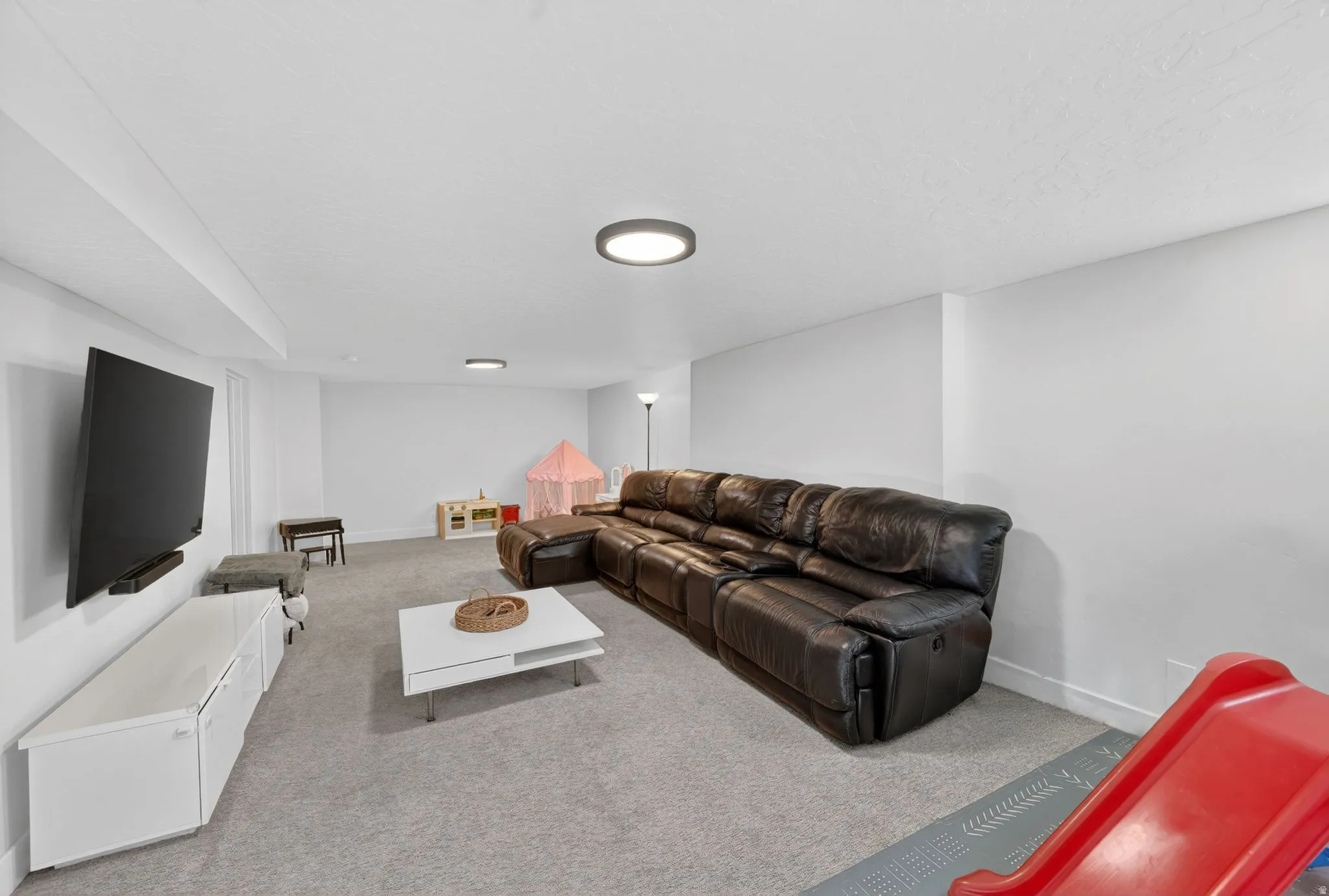 Spacious recreation room featuring light gray carpeting and white walls