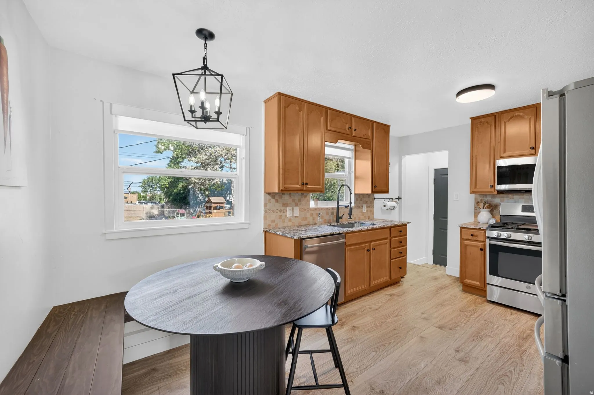 Kitchen featuring wood-finish flooring, light wood cabinetry, stone-finish countertops, and stainless steel appliances