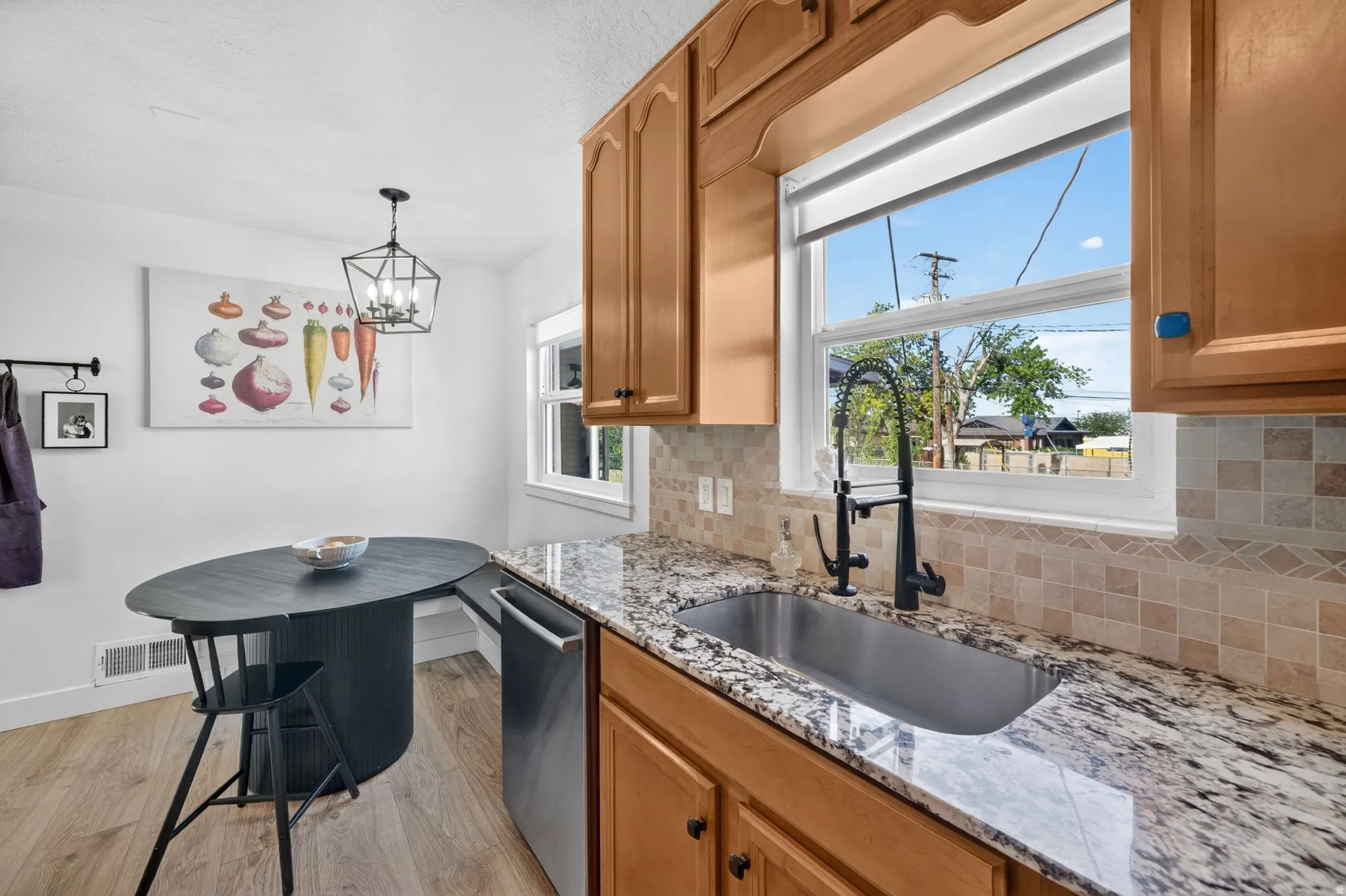 Kitchen featuring light wood-finish cabinetry and a stainless steel sink with a matte black faucet