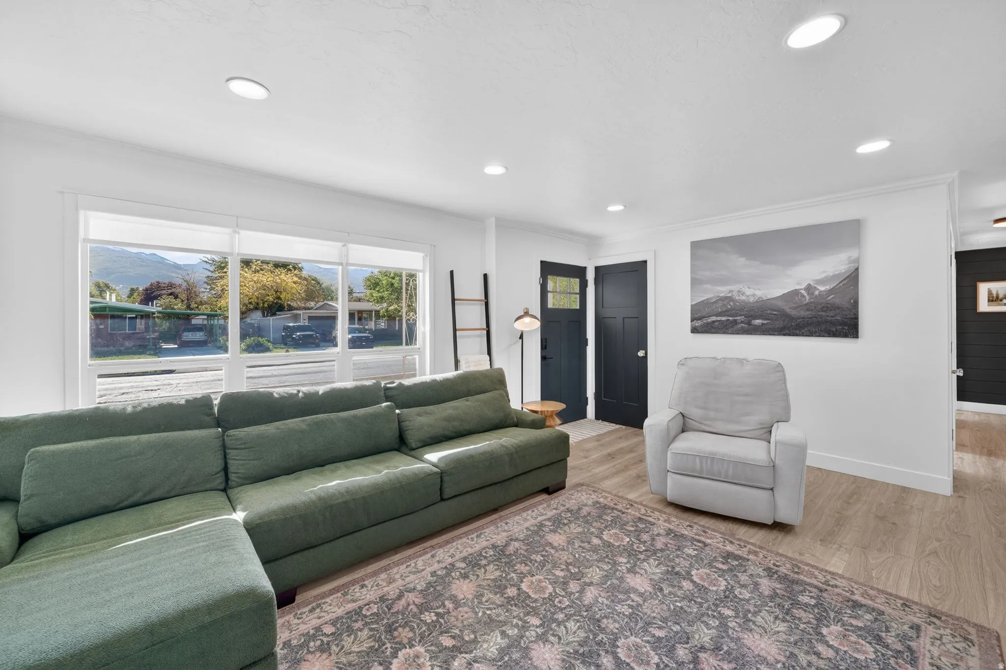 Spacious living area featuring light wood-finish flooring and ample recessed lighting