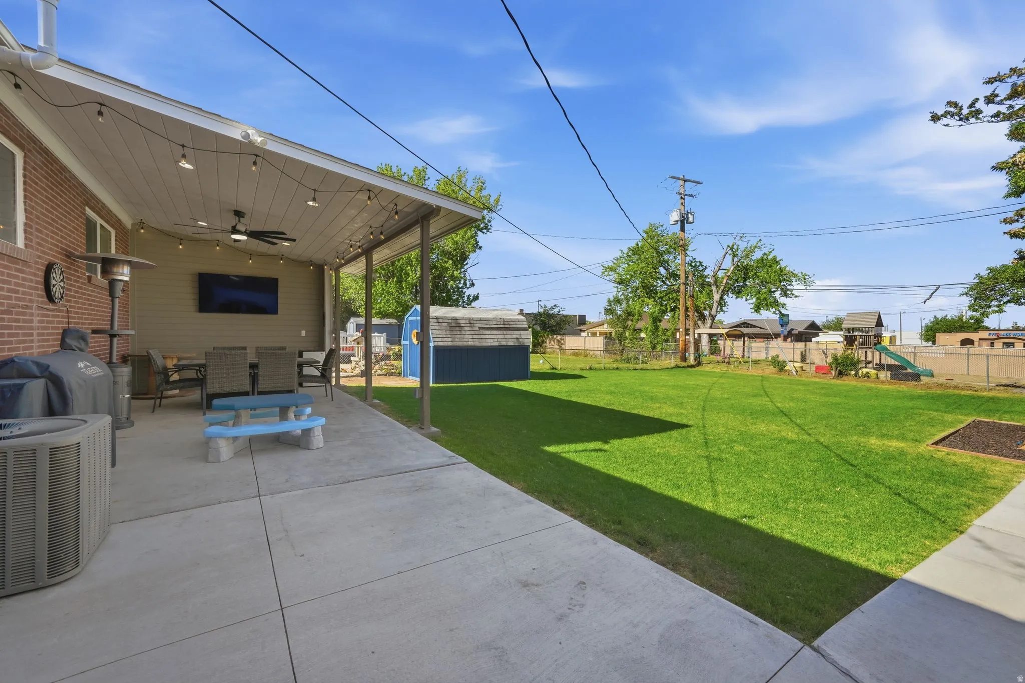 Expansive concrete patio featuring a covered section with a ceiling fan and string lighting