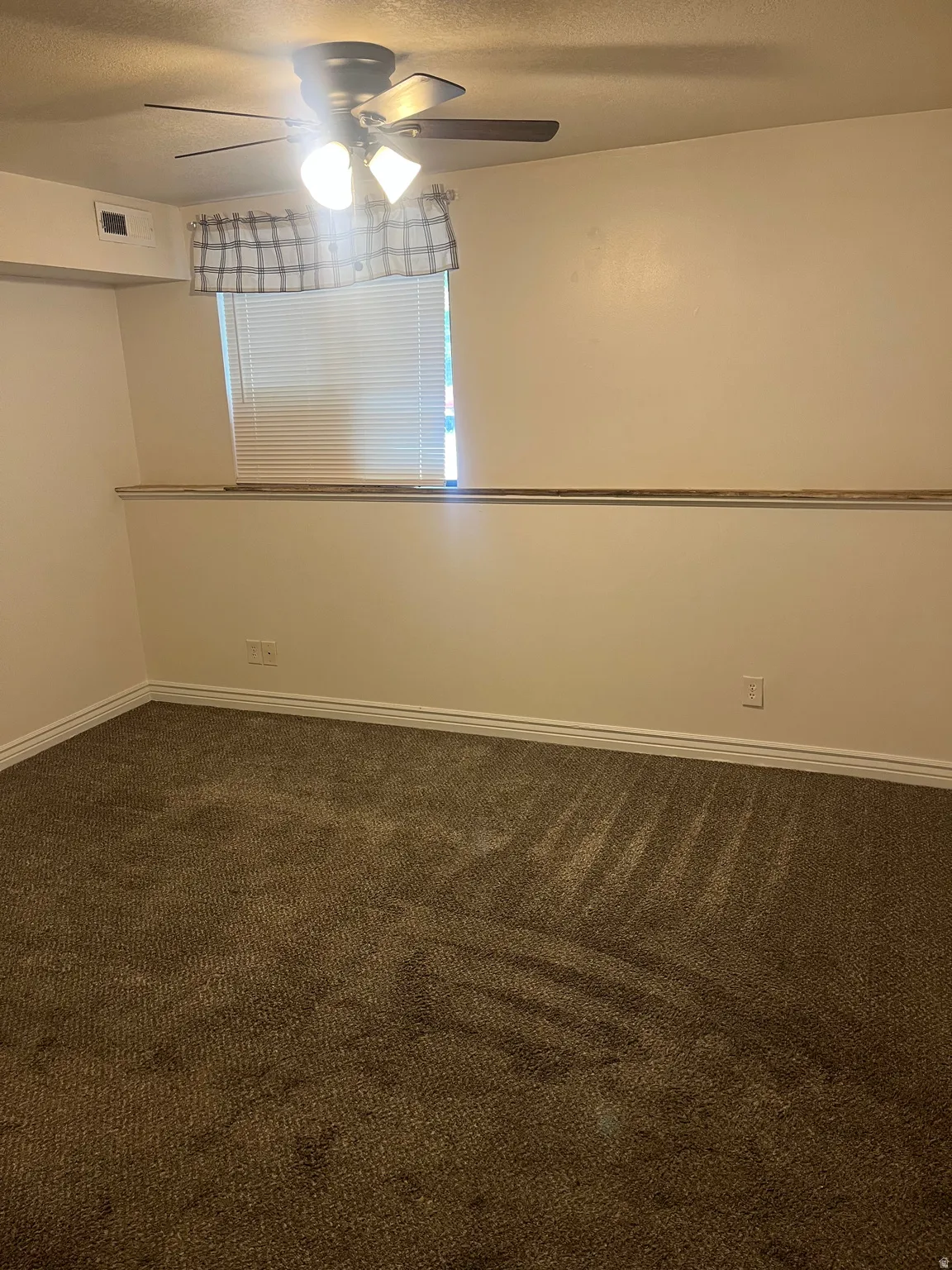 Carpeted room featuring a ceiling fan with integrated lighting, a window with horizontal blinds, and white baseboards