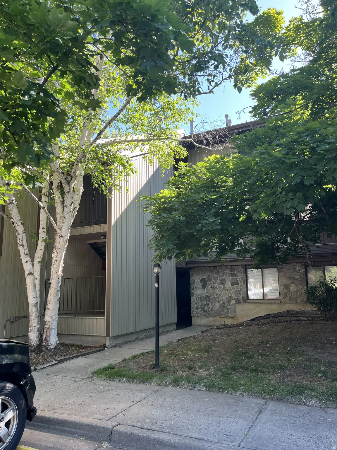Multi-level building exterior featuring a stone facade and vertical siding