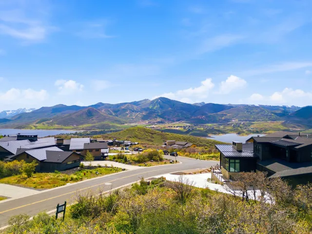Mountainous landscape featuring a prominent lake and a residential street with multiple contemporary homes