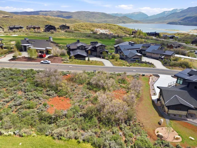 Expansive land parcel featuring natural shrubbery and surrounding mountain and water scenery