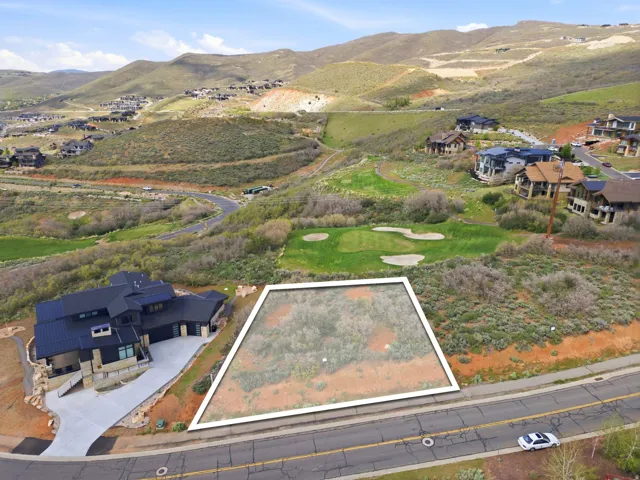 Generous lot bordered by a paved road, featuring a natural, undeveloped landscape and surrounded by rolling hills