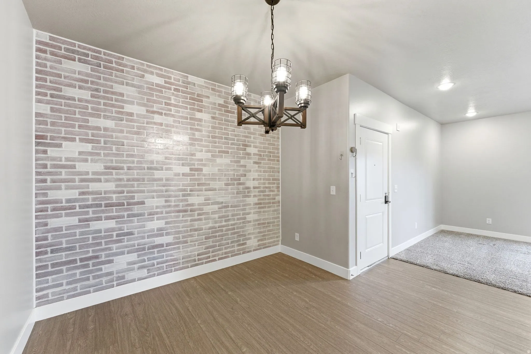 Accent brick wall with wood-finish flooring and a rustic chandelier