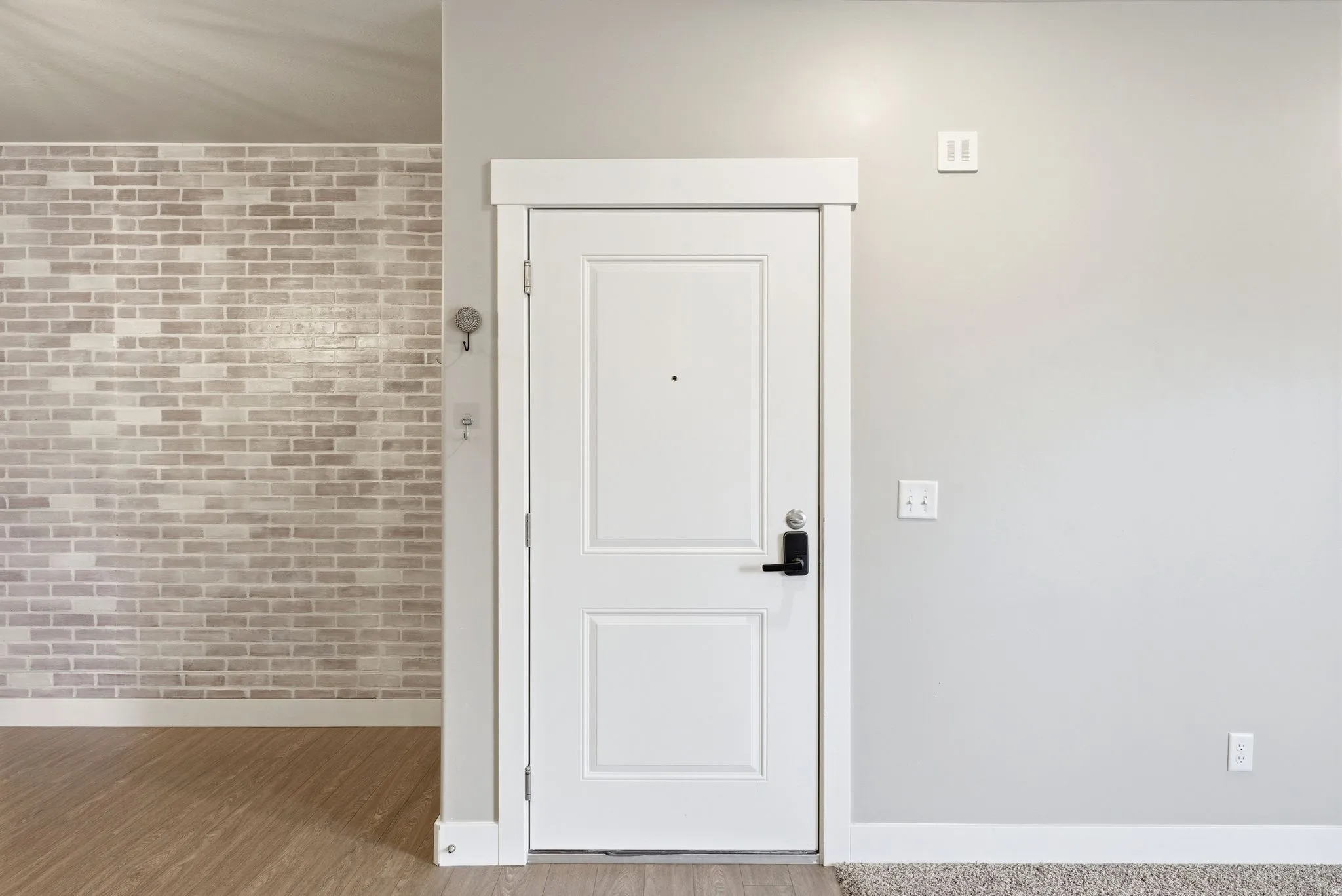 Entryway featuring a white paneled door with black hardware, complementing the light gray wall