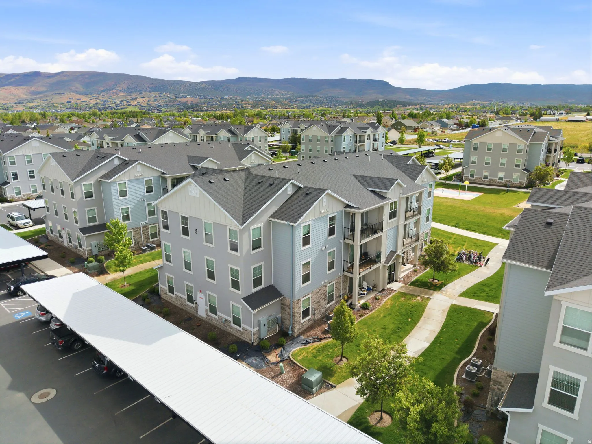 Multi-story apartment building featuring light blue siding, stone veneer accents, and multiple balconies