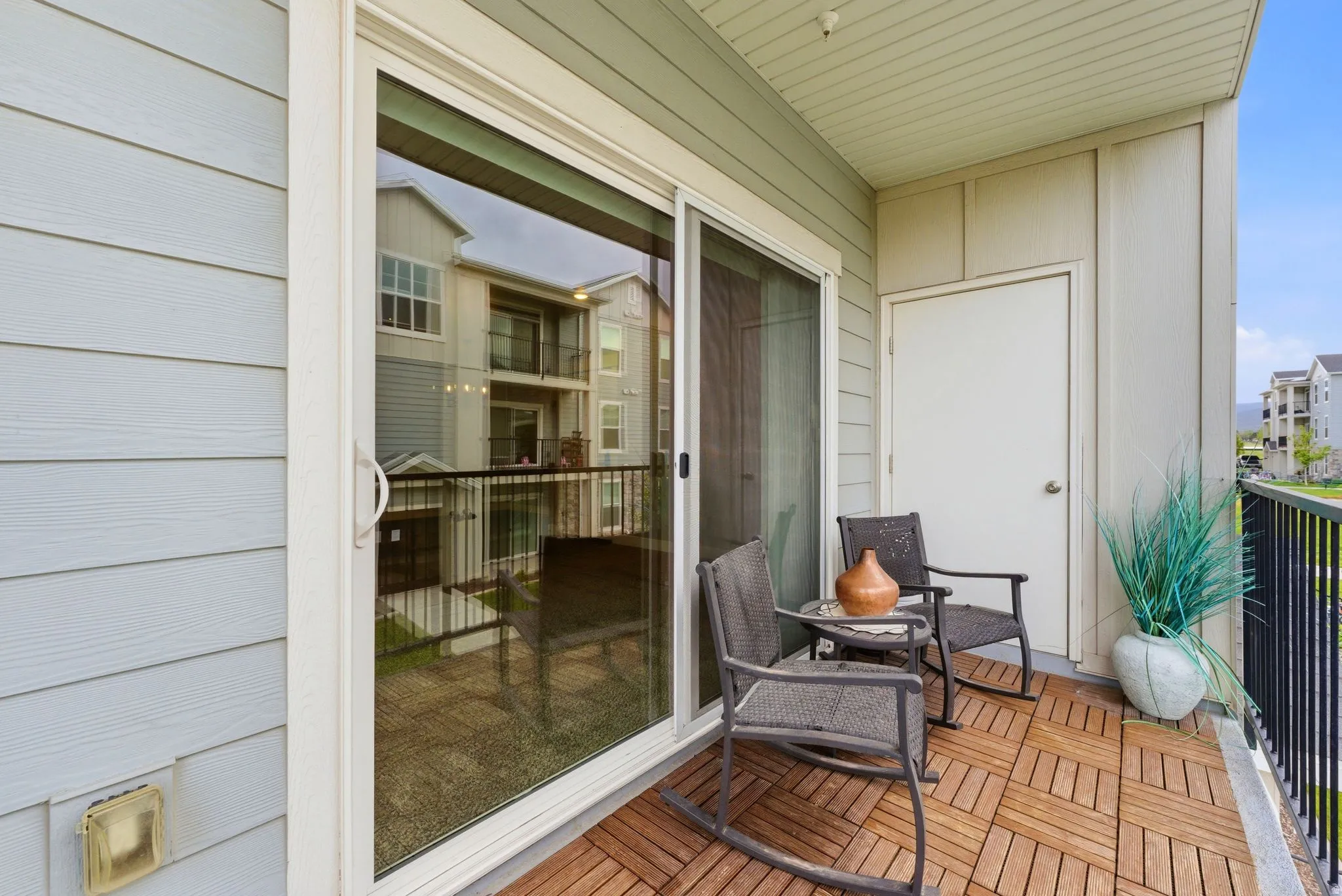 Private balcony featuring wood-finish floor tiles, a sliding glass door, an exterior storage closet, and a black metal railing