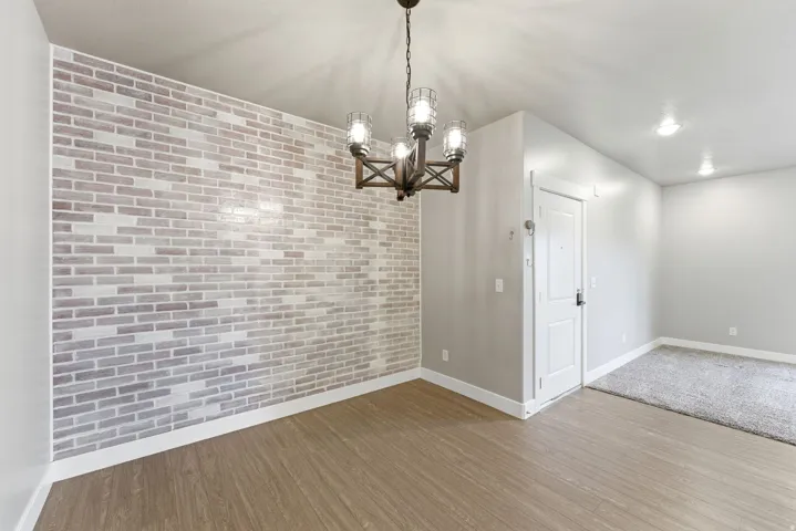 Accent brick wall with wood-finish flooring and a rustic chandelier