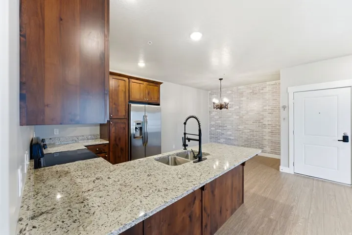 Kitchen featuring wood cabinetry, stainless steel appliances, granite countertops, and a dual basin sink with a black fixture