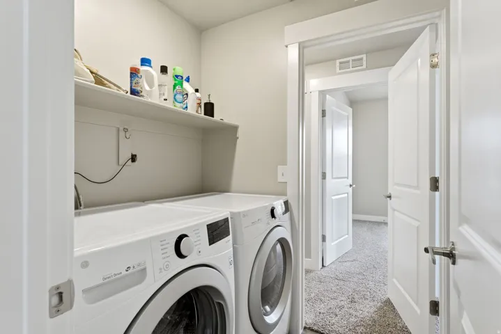 Laundry area featuring a built-in white shelf for storage, light gray wall paint, and white trim molding