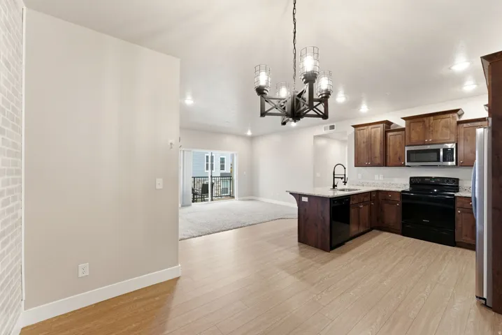 Modern kitchen featuring wood-finish flooring, dark wood cabinetry, granite countertops, and stainless steel appliances