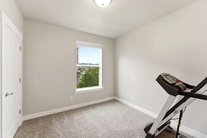 Compact room featuring light gray walls, plush carpet flooring, white trim, a single window, and a flush mount ceiling light fixture