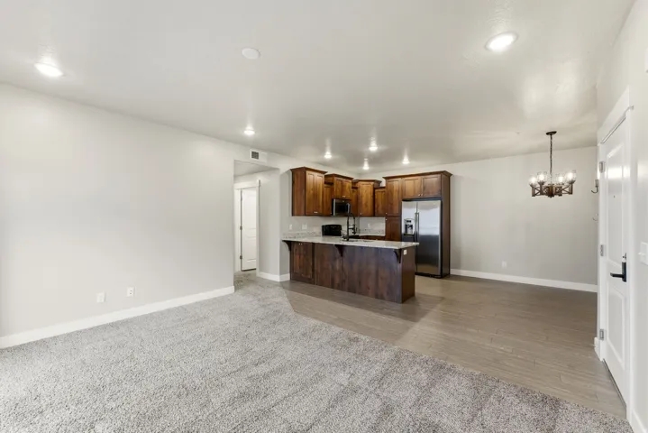 Open-concept living area featuring a kitchen with wood cabinetry, stainless steel appliances, and a breakfast bar
