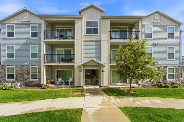 Contemporary multi-story building featuring light blue horizontal siding, stone veneer accents, and white trim