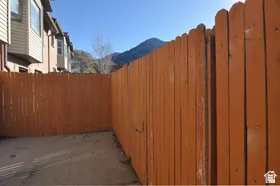 Private outdoor space featuring a wood fence, concrete ground cover, and mountain scenery