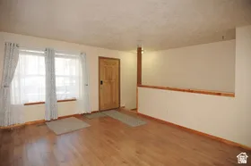 Entryway featuring a carved wood door, light wood-finish flooring, and a pair of windows