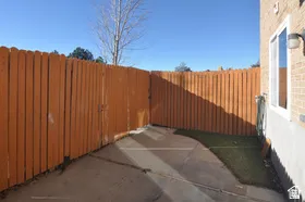 Fenced yard area featuring a concrete patio, artificial turf, and a wood privacy fence with gate