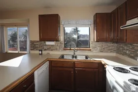 Kitchen featuring wood cabinetry, stone-look tile backsplash, and a double basin stainless steel sink