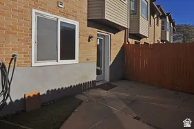 Private outdoor patio space featuring a solid wood privacy fence, brick exterior, and direct access door