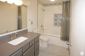 Bathroom featuring a gray vanity with an integrated sink, brushed nickel faucet, and a large wall mirror