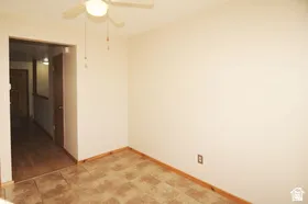 Room featuring a ceiling fan with light fixture, neutral wall color, and patterned floor tiles