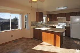 Kitchen with wood-finish cabinetry, light countertops, and a tiled backsplash