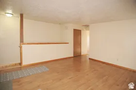 Spacious interior room featuring wood-finish flooring, light-toned wall paint, and a textured ceiling