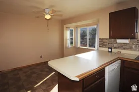 Kitchen area featuring dark wood-finish cabinetry, light-toned countertops, and a stone-look tile backsplash