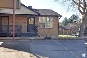 Brick exterior with a gabled roofline, multiple entryways, and a covered porch with railings