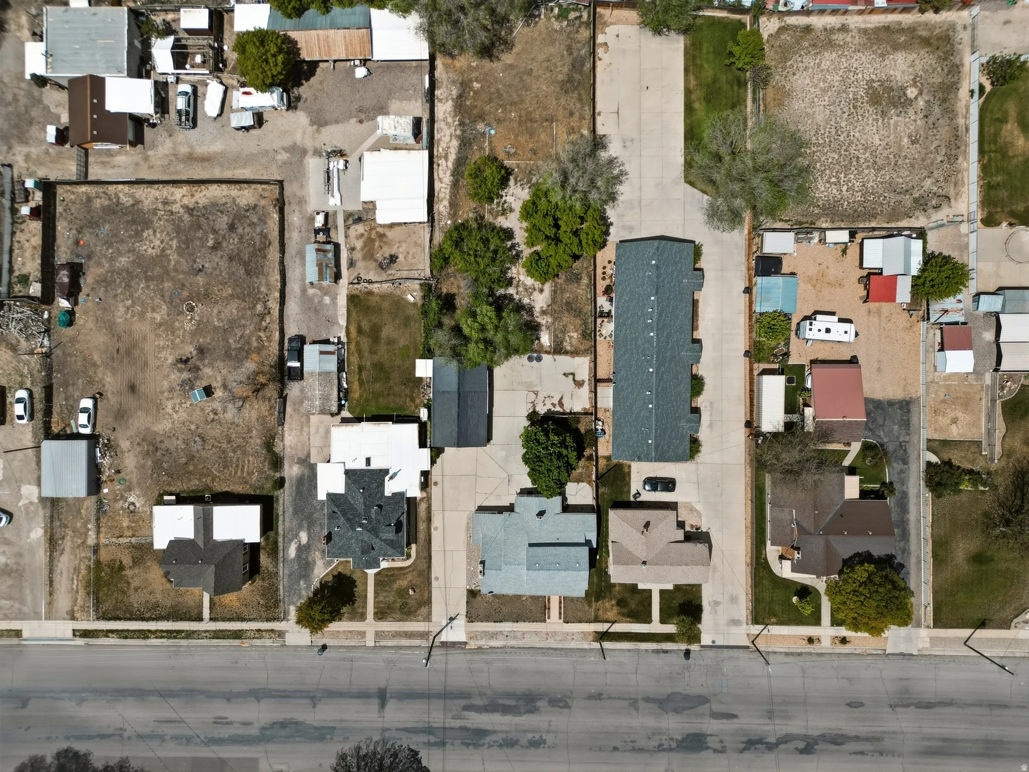 Aerial overview showcasing multiple distinct properties, including residential structures with various rooflines and surrounding land parcels