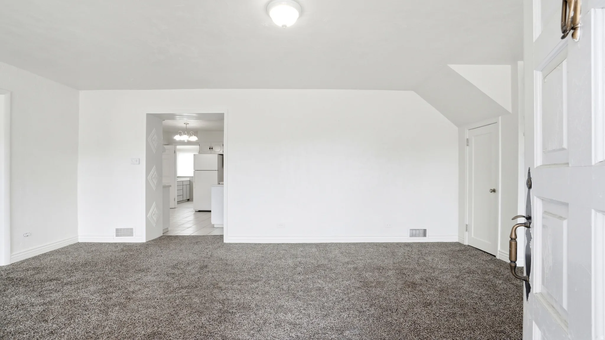 Spacious living area featuring neutral carpeting and white wall finishes