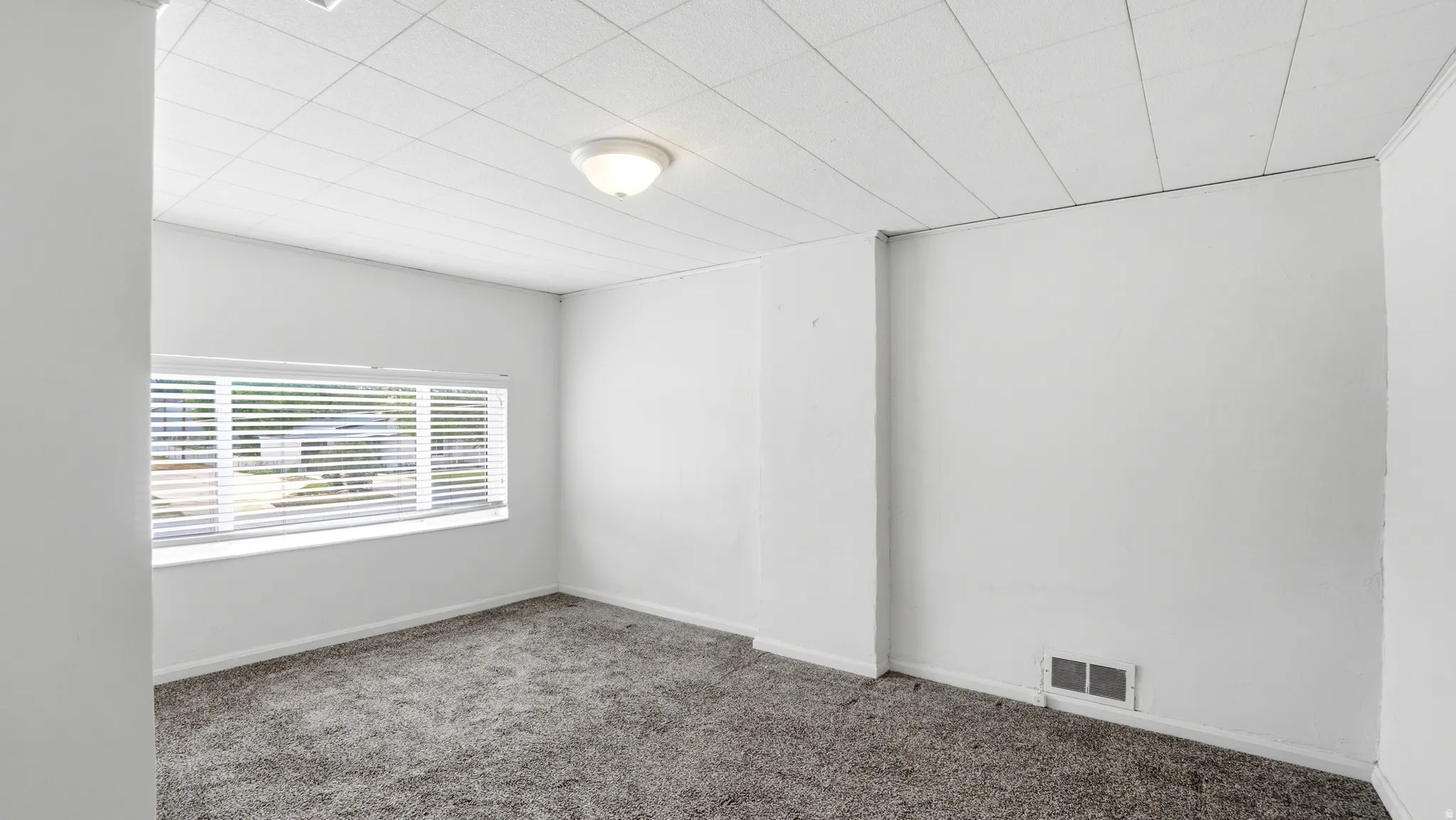 Room featuring wall-to-wall carpeting, white walls, and a drop panel ceiling with recessed lighting