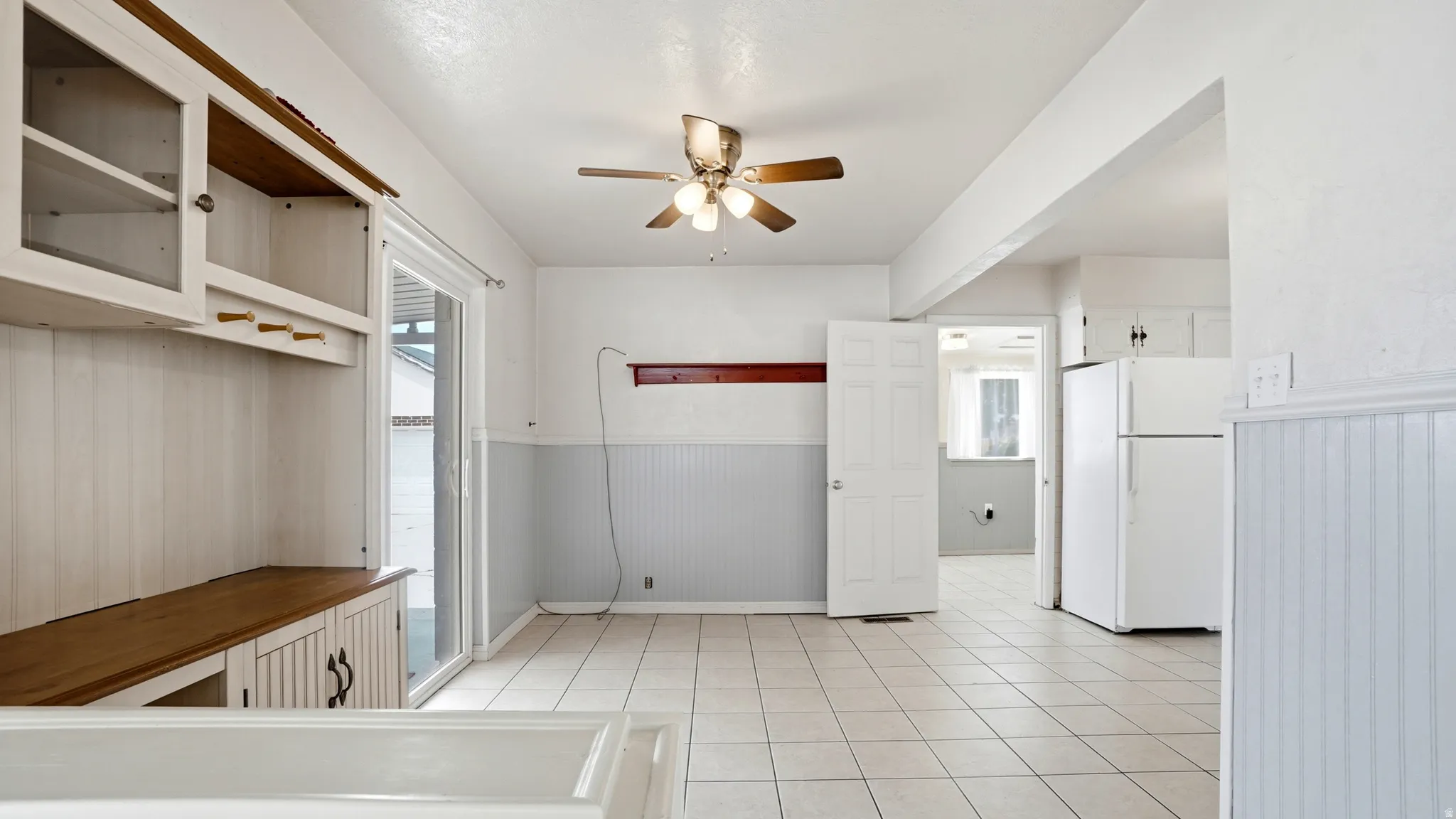 Dining area with tile flooring, built-in hutch, ceiling fan, and sliding glass door