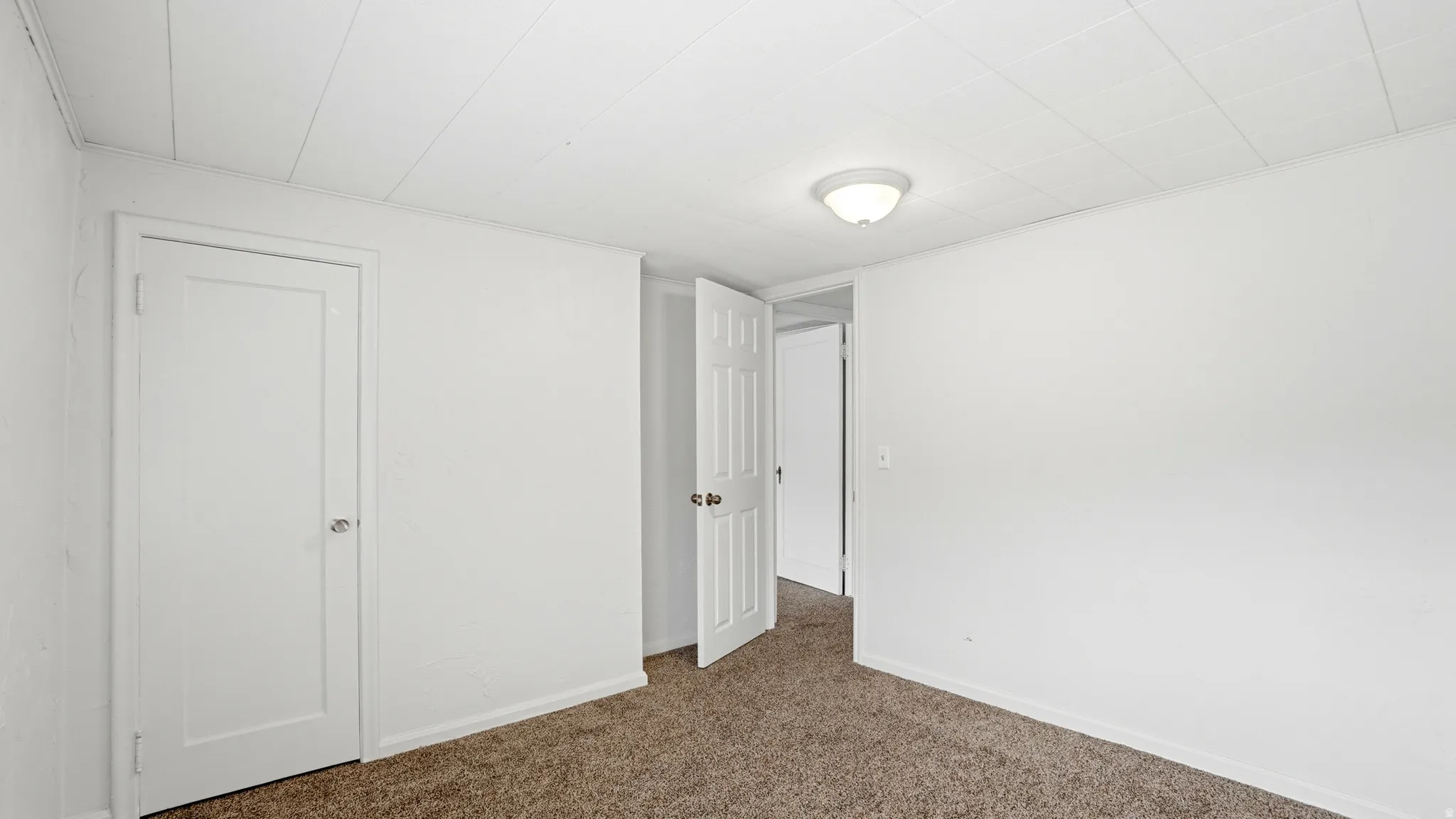 Carpeted room with white walls, a white ceiling with paneling, and a flush mount light fixture
