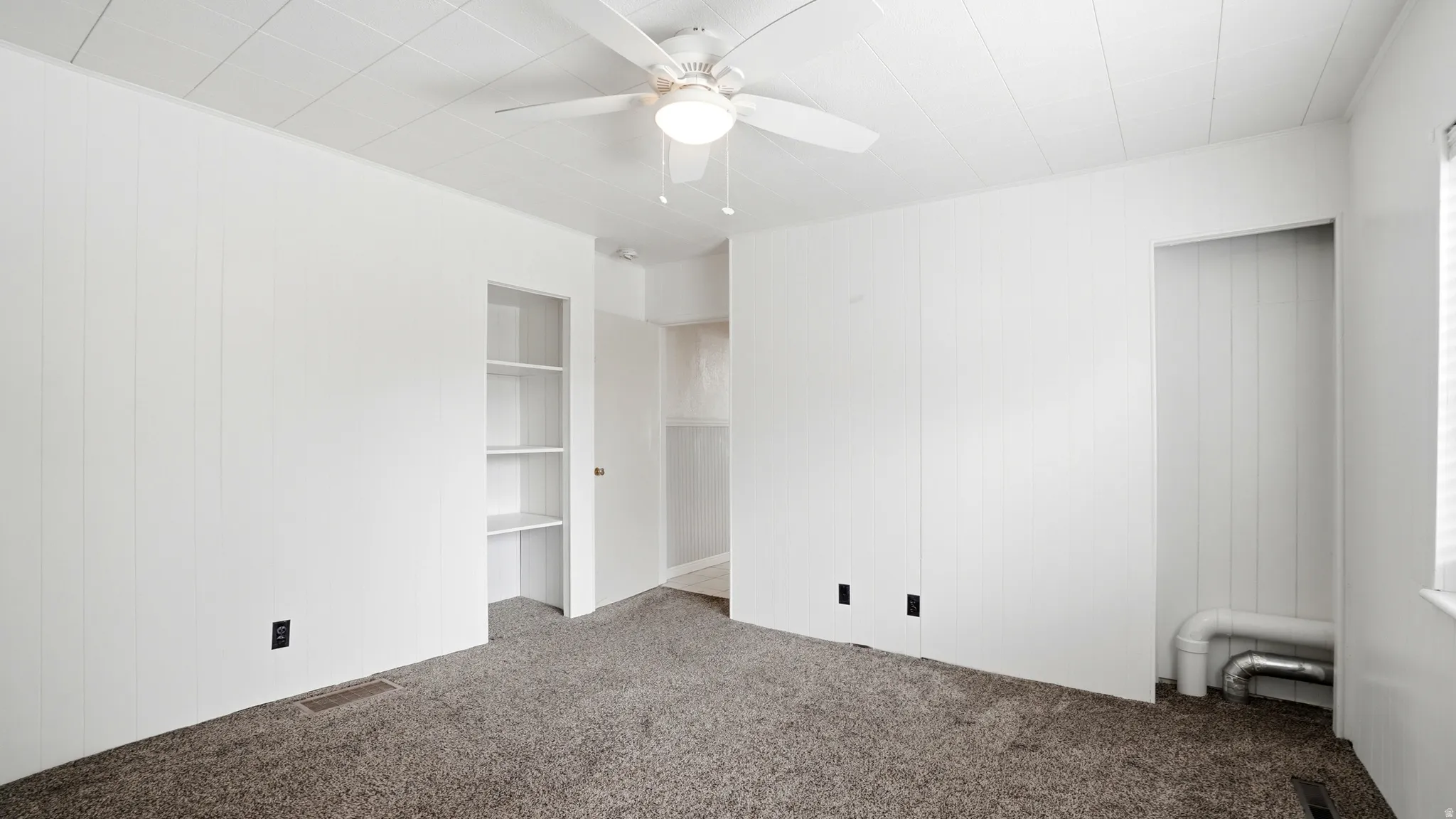 White-paneled walls with textured ceiling and a ceiling fan with integrated lighting