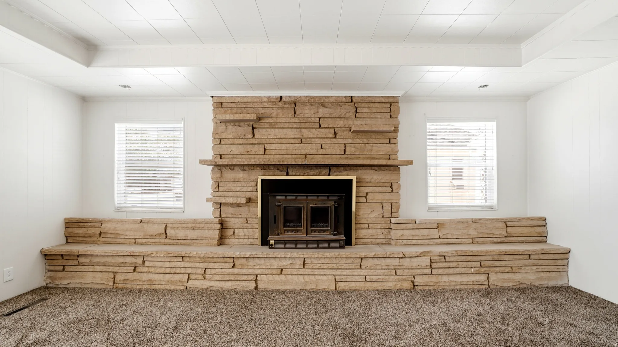Stone-clad fireplace featuring an integrated wood-burning insert and an extended stone hearth