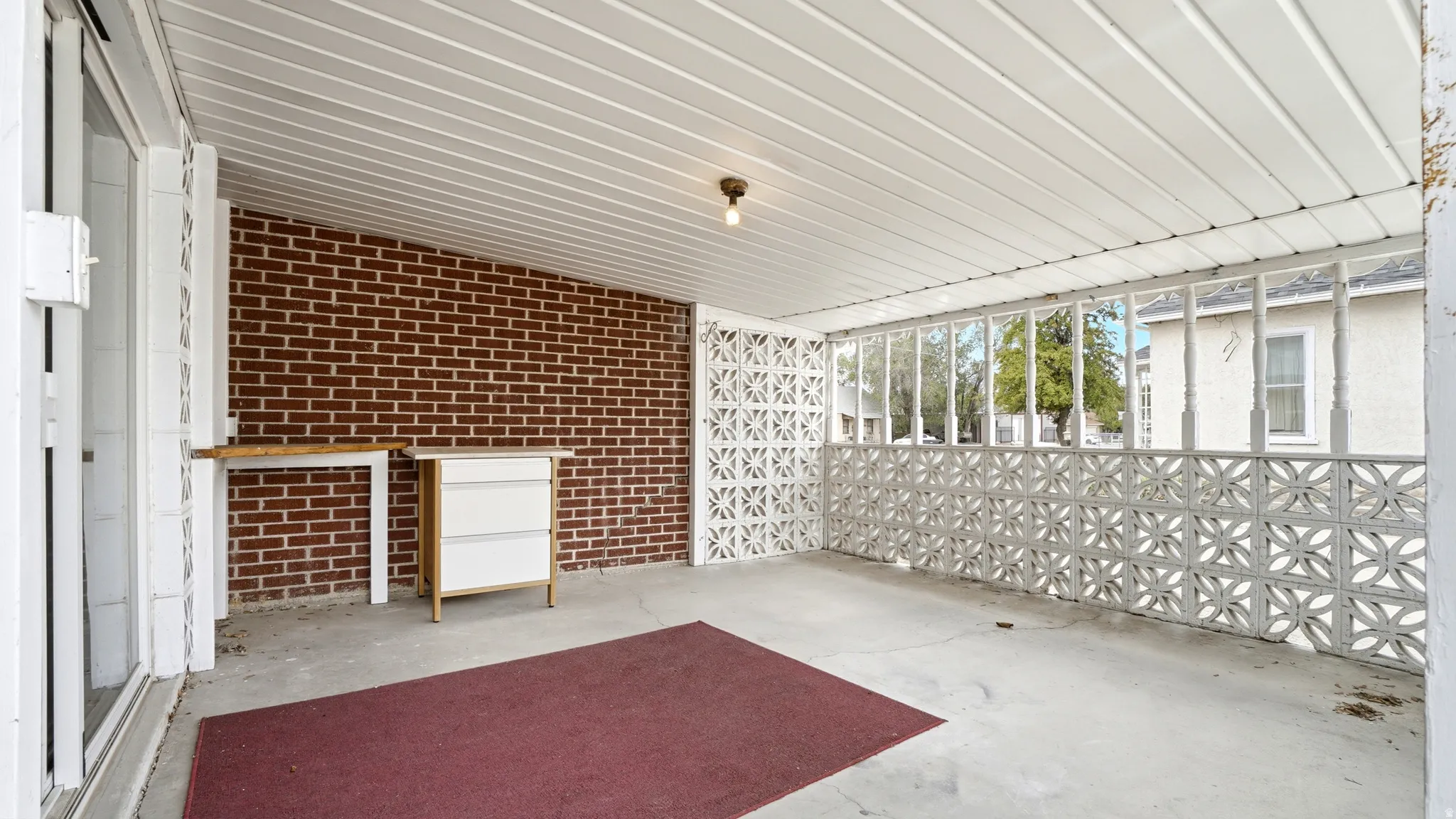 Covered patio featuring a concrete floor, brick accent wall, and decorative block screen
